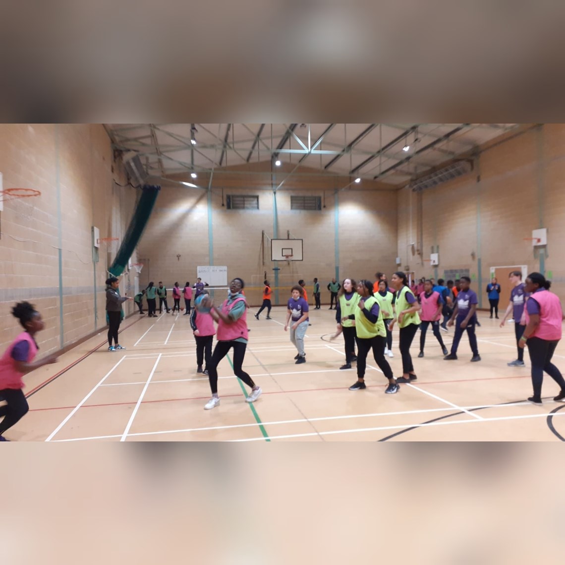 Guardian Ballers action shot - a group of boys and girls play basketball in their school hall